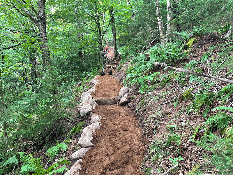 Conservation volunteers and professionals performing trail maintenance and construction with safety gear