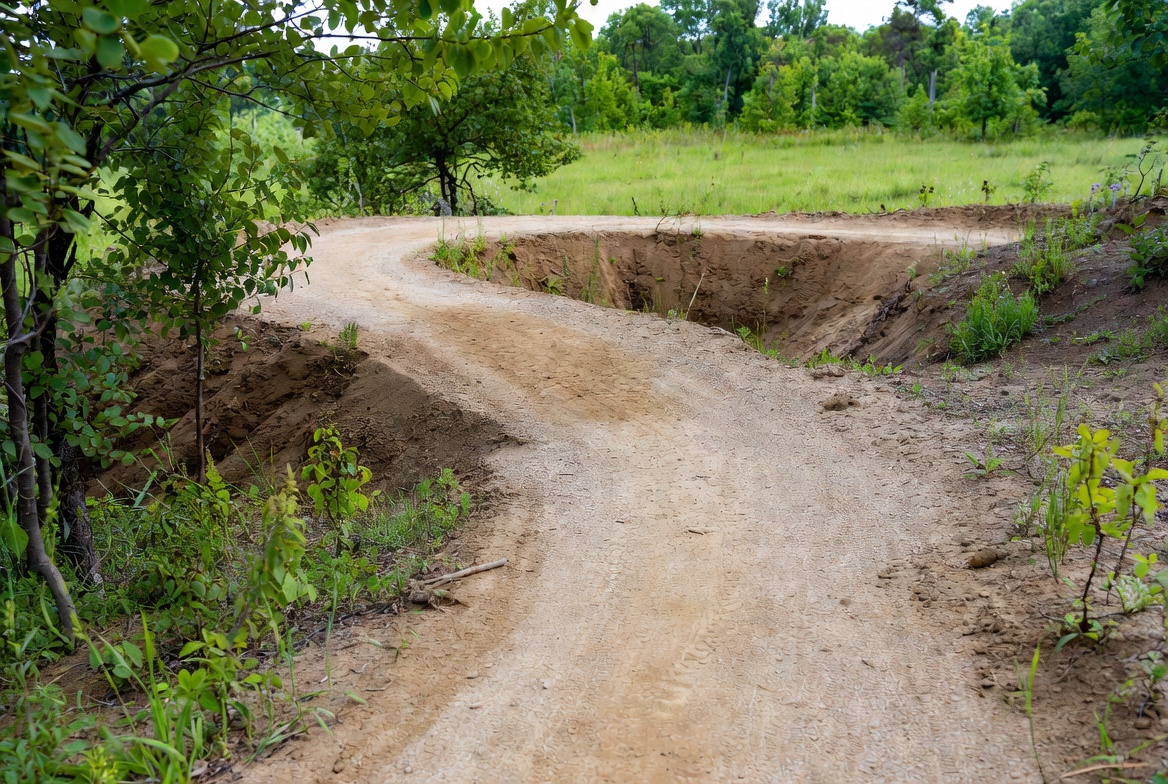 Newly constructed multi-use trail winding through forested landscape with erosion-control features, representing bonded sustainable trail projects